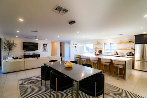 Open-concept great room with a spacious sectional, abundant natural light, a large HDTV with cable, and seamless flow to the dining area and fully equipped kitchen.