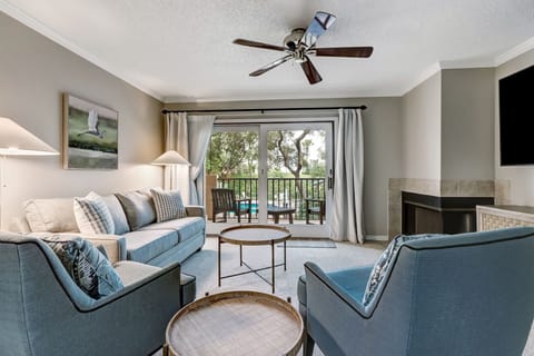 Beautifully Furnished Living Space with Two Chairs and a Sleeper Sofa Situated around a Large Flat Screen Smart TV (Fireplace not Functional)