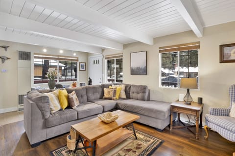 Cozy mountain living room with wood ceilings, stone fireplace, comfy seating, and smart TV—perfect for relaxing evenings, movie nights, and warm cabin vibes after outdoor adventures.