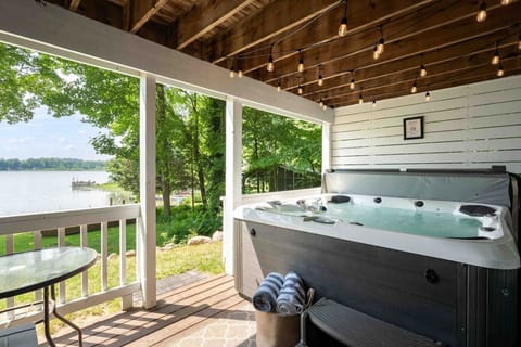 Covered deck with a hot tub and scenic lake views.