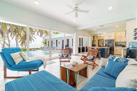 Open-concept living room with tropical decor, cozy seating, and seamless flow into the fully equipped kitchen on Ambergris Caye