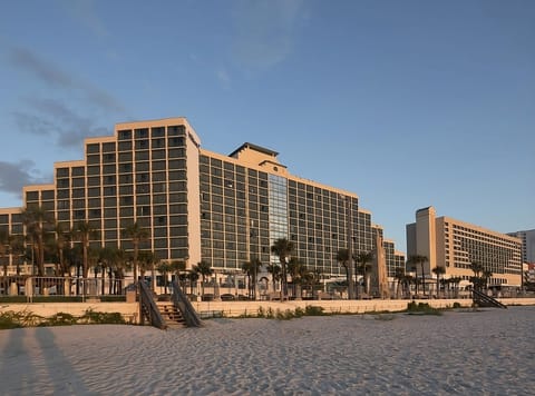 Step onto soft sand with the resort rising behind you.