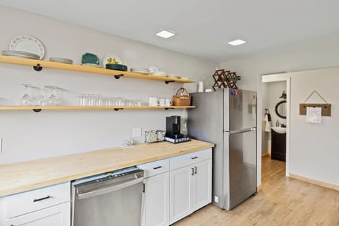Fully stocked kitchen with cookware, utensils, plates and glassware.
