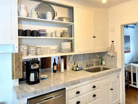 Stocked kitchen with plates, bowls, coffee cups and coffee maker