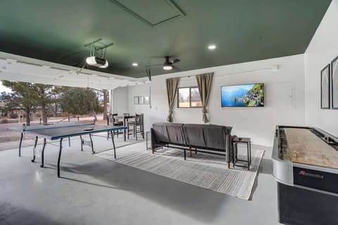 Perfect for family/friendly game nights, the garage game room is incredibly equipped with a ping pong table, shuffleboard, a large Smart TV, and a futon for additional relaxation..
