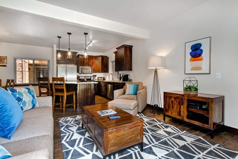 Relax in this bright living room that opens into the kitchen and dining space. With a stylish rug, warm lighting, and thoughtful decor, it's designed for comfort and connection — great for both quiet evenings and lively gatherings.