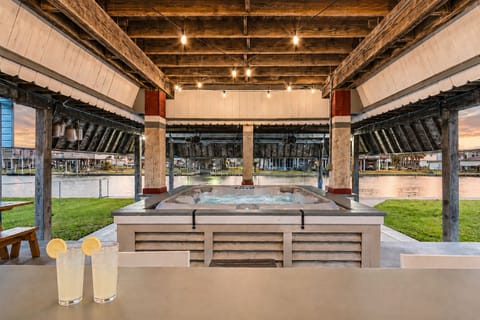 Large covered patio with outdoor seating, warm string lighting, and open-air canal-side gathering space in Galveston, TX.