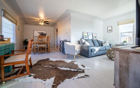 Spacious living area with couch, chair, TV, desk and dining table.