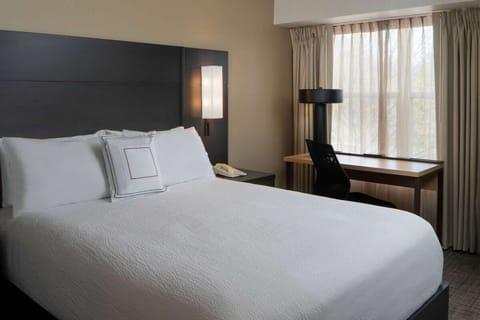 Sink into crisp bedding beside soft daylight and calm views.