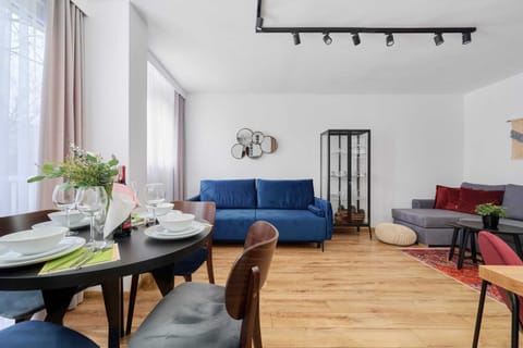 A stylish living room with a blue sofa, wooden furniture, and a cozy dining area, creating a warm atmosphere.
