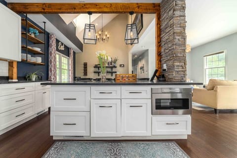 Enormous soap stone island with built in microwave, antique wood beam and custom stone wall.  Custom Industrial Wall Mount Iron Pipe shelves stocked with plenty of dishes