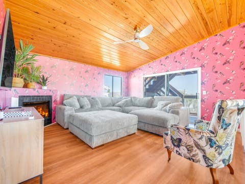 The living room has a large sectional, 65" television and a decorative fireplace.