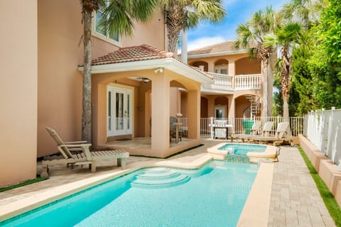 Mediterranean-style villa with private swimming pool surrounded by tropical palms, featuring covered terraces and multiple outdoor lounging areas for relaxation.