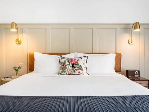 Sink into crisp linens beneath warm brass bedside lighting.