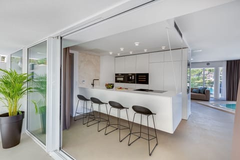 Kitchen island with high chairs and kitchen equipped with oven, microwave, fridge and coffee maker