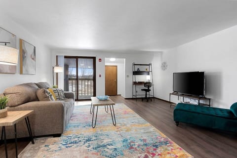 Bright + spacious living room. Features comfortable furnishings, smart tv, designated workspace, and balcony.