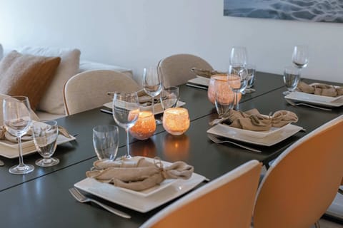 Elegant dining setup with seating for six, stylish neutral decor, soft candle lighting, and cozy pillows—perfect for intimate dinners or entertaining guests in comfort and style.