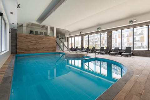 A luxurious indoor pool area with large windows, modern tiling, and a relaxing ambiance.