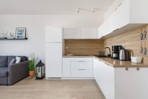 A fully equipped kitchen with white cabinets, wooden countertops, and a clean design.