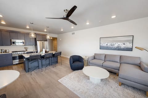 Relax in this airy, modern living room featuring a cozy stone fireplace and large windows with mountain views. The open layout and stylish furnishings make it the perfect spot for relaxing.