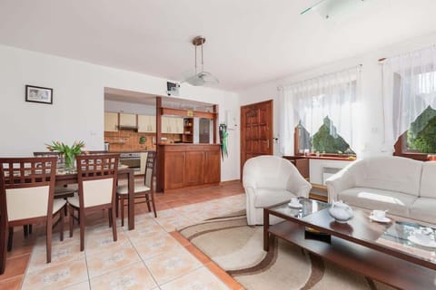 A spacious living room featuring wood-paneled cabinets, a sofa, and access to the kitchen.