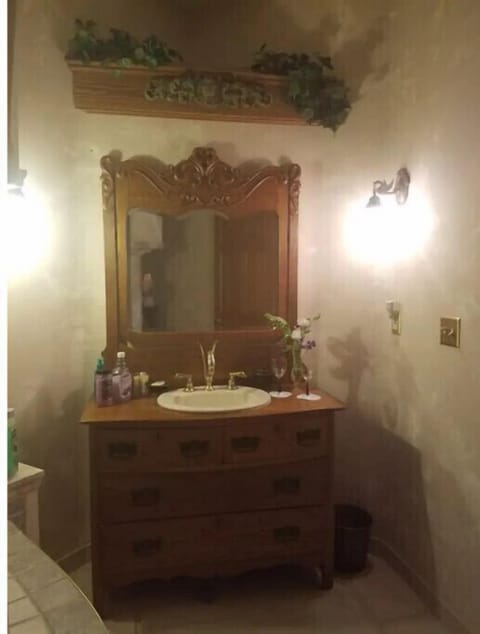 Bathroom features antique vanity and brass wall sconces.