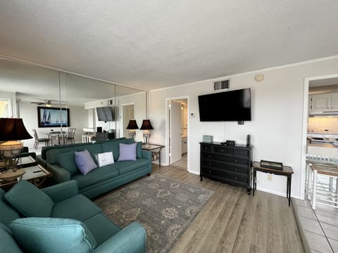 Unwind in your spacious living room with teal sofas, flat-screen TV, and elegant furnishings that create the perfect retreat for relaxation.