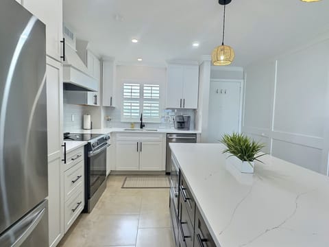 Kitchen with island seating, stainless steel appliances, pendant lighting, and white shaker cabinets
