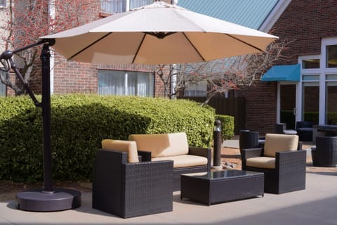 Unwind outdoors on cushioned seating beneath a shady umbrella.