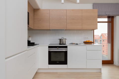 A modern kitchen with light wood cabinets, integrated appliances, and ample workspace.