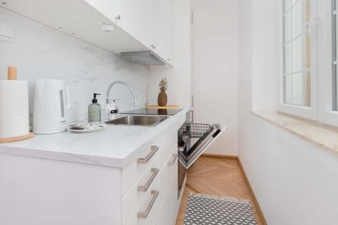A bright and modern kitchen area with a marble countertop, sink, and white appliances for a clean look.