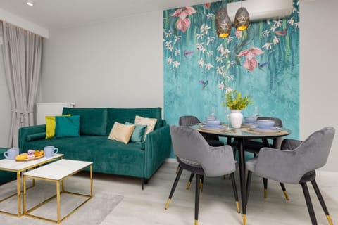 A vibrant dining area with a teal accent wall, round table, and comfortable gray chairs.
