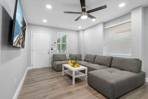 Living room with spacious sectional sofa, flat-screen TV, and ceiling fan — a comfortable spot to relax after exploring Tampa.