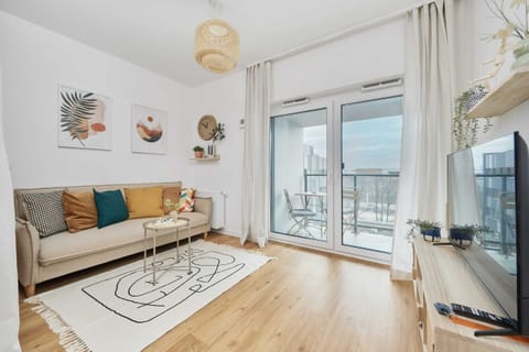 A cozy living room with a stylish sofa, bright decor, and access to a balcony.
