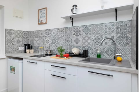 A small yet functional kitchen with white cabinets and a neutral backsplash. The countertop is accessorized for meal prep.