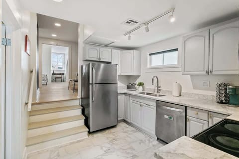 Bright downstairs kitchen with marble-style floors, stainless appliances, and plenty of counter space. Conveniently located near the lounge and bedroom areas for easy meals and morning coffee.