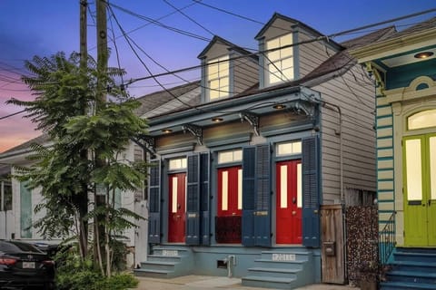 A classic Creole façade glows at dusk with bold red doors, shuttered windows, and historic trim. Just steps from Frenchmen Street and an easy walk to the French Quarter’s music, food, and nightlife.
