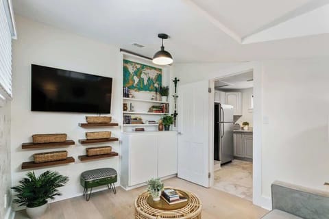 Upstairs lounge with large TV, cozy seating, and built-ins stocked with books and storage baskets. A comfortable spot to unwind, work, or stream after exploring the Quarter.