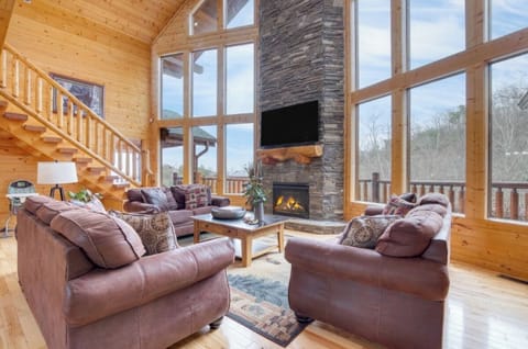 Sink into plush leather sofas beside your crackling stone fireplace, with soaring windows framing mountain views in this luxurious cabin retreat.