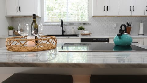 `Modern Elegance Meets Homely Warmth: Enjoy the best of both worlds in this stunning kitchen, where the glistening countertops and a bottle of wine await your arrival. Perfect for intimate dinners or a quiet night in. #ModernHome #CozyKitchen #WineLoversR