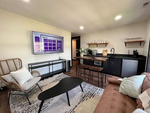 Living Room: In the living area, there's a cozy leather love seat, an accent chair, a coffee table, and a big smart TV.