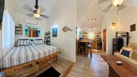 King bed with striped bedding sits next to a living area featuring a wooden coffee table and futon sofa.
