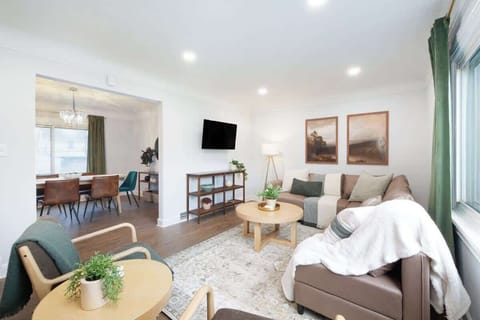 - Comfortable living room with sectional seating   - Wall mounted TV and bright windows with views   - Open design connects to dining and kitchen area  