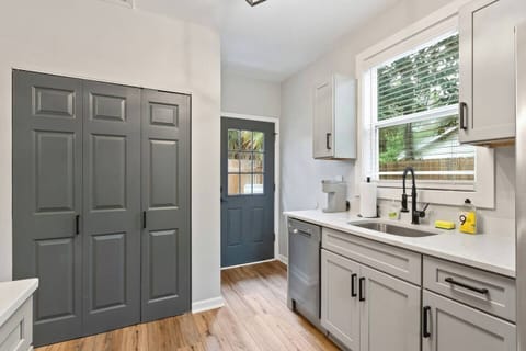 Full kitchen with dishwasher, quartz counters, laundry, and door to privacy fenced backyard.