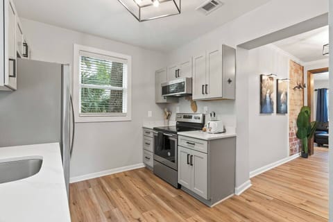 Full kitchen with quartz counters and stainless steel appliances including a full sized fridge, range, and a dishwasher. 