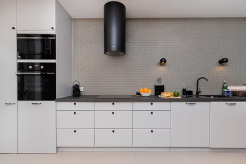 A sleek white kitchen with minimalist cabinets and black accents, featuring a functional and stylish design. The workspace is bright and well-organized.