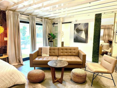 Open living area with a faux-leather couch as an added sleeping space, 65” Smart TV, high-speed WiFi internet service, vaulted ceiling and dining area for 4 people.