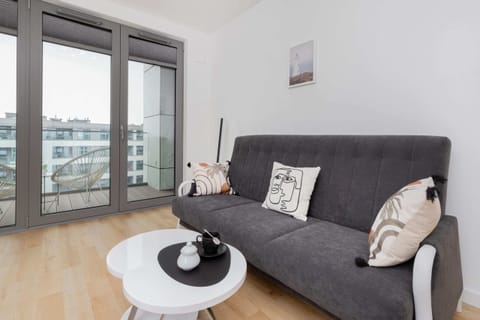 Modern living room with a comfortable grey sofa, a stylish coffee table, and large windows providing plenty of natural light.
