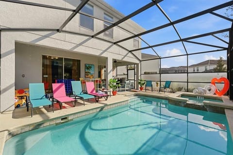 Private screened-in pool with colorful loungers, perfect for sunny days and relaxed family fun.