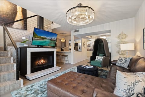 The spacious living room boasts an inviting fireplace and an open-concept design, with a massive TV serving as the focal point for both relaxation and entertainment.